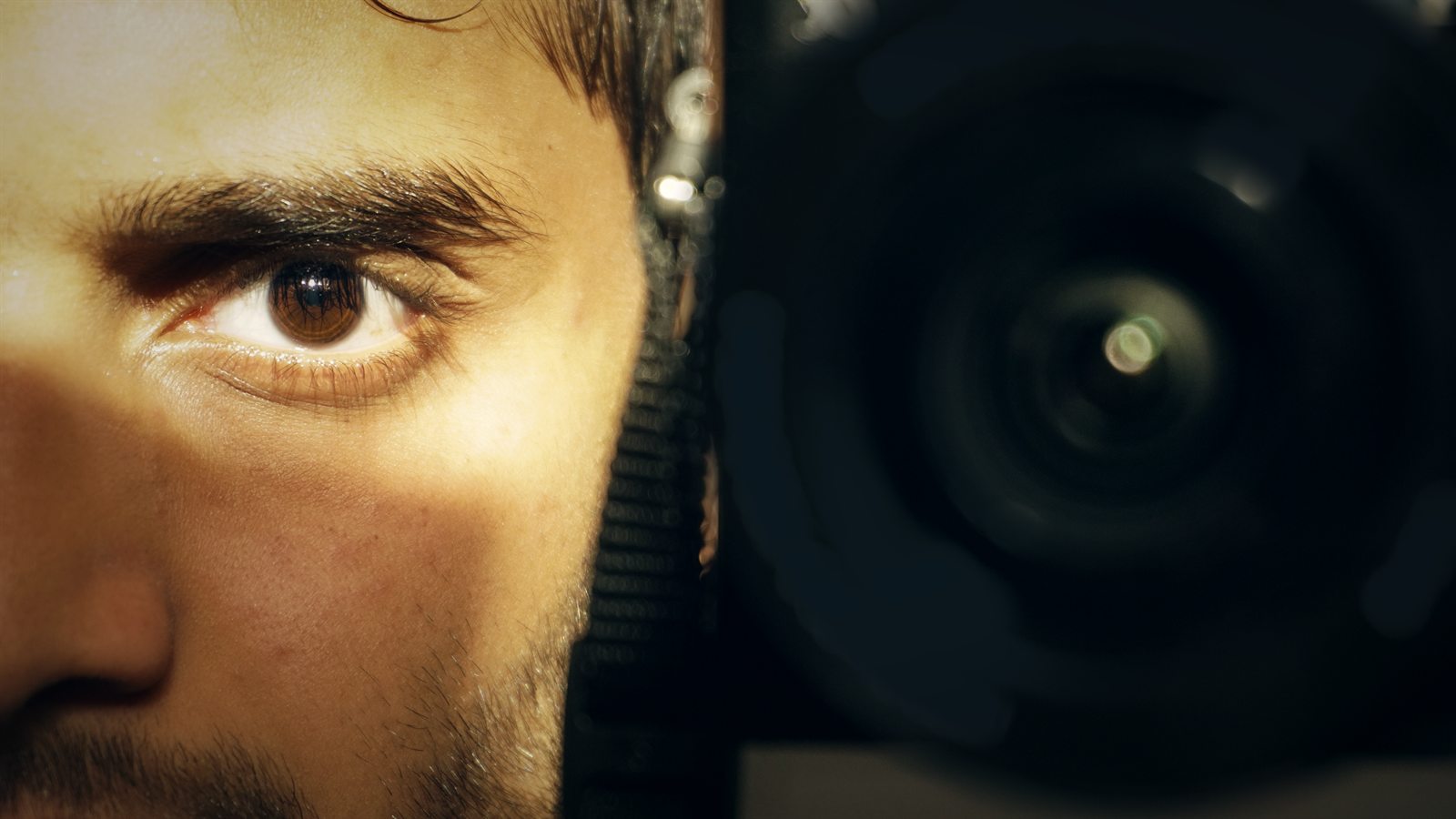 Close-up of the photographer's eye beside a camera lens